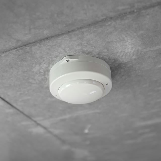 Round white alarm mounted on a ceiling, the backstop for a combustion safety problem