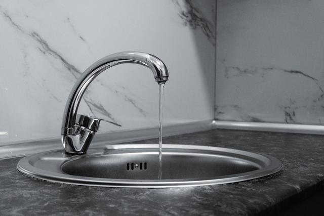 Water running from a chrome kitchen faucet into the sink