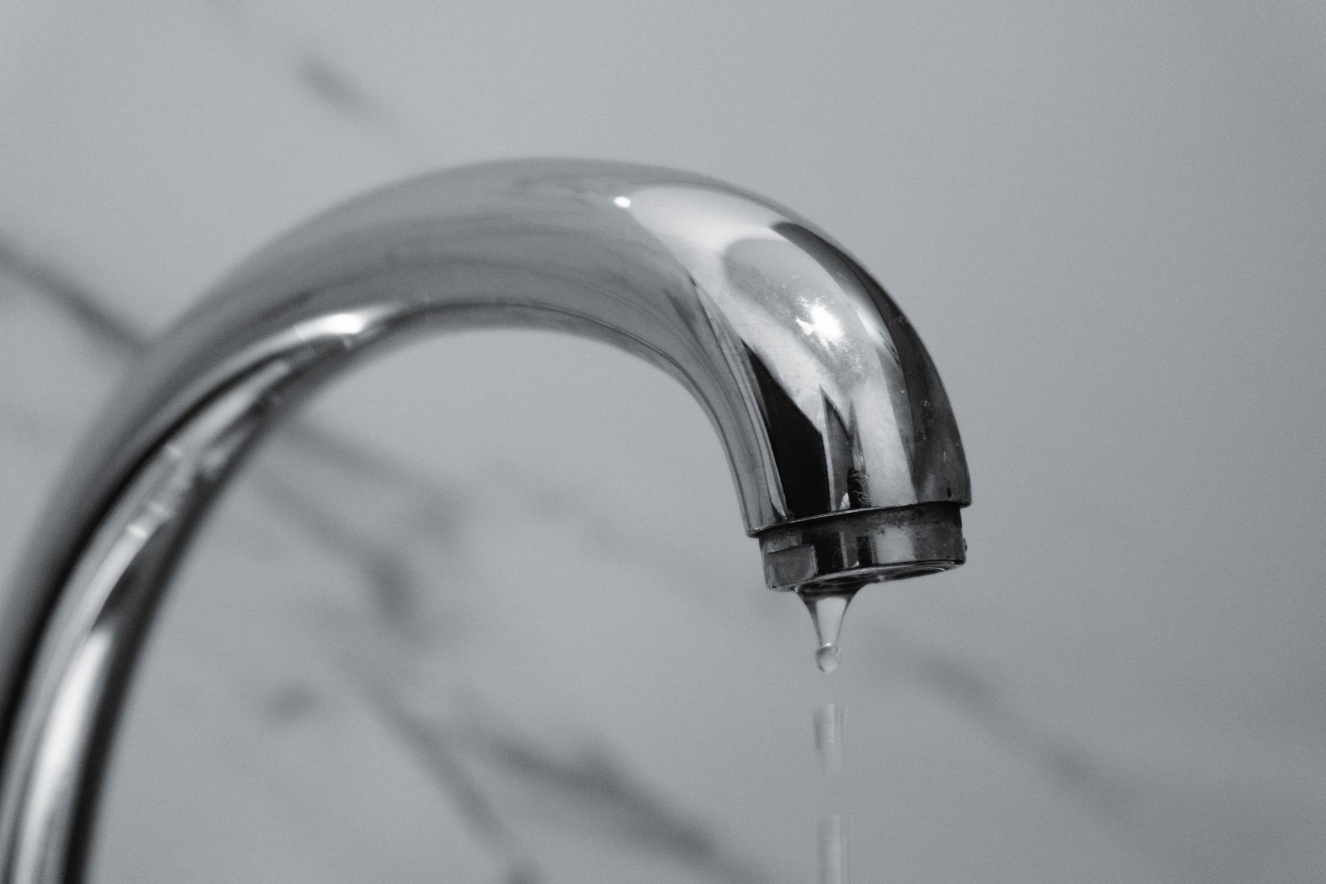 Water dripping from a leaky chrome bathroom faucet