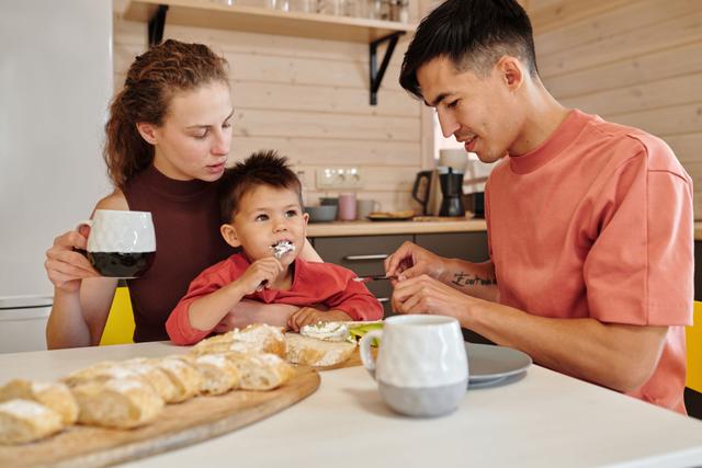 Parents feeding a toddler at a kitchen counter