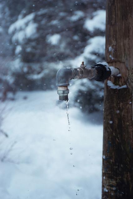 Outdoor faucet dripping in the snow during a hard freeze