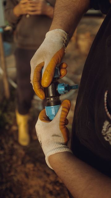 Gloved hands making up a threaded pipe fitting