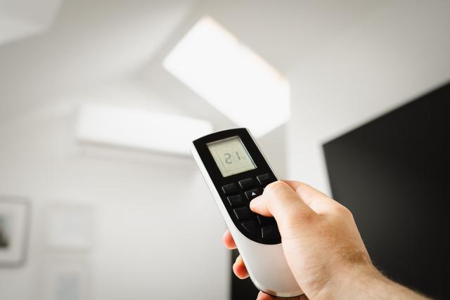 Hand pointing a remote at a wall mounted mini split
