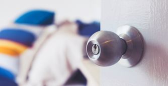 Hand reaching for the silver knob of a white interior door