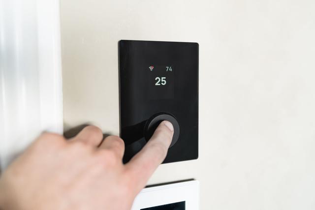 Hand pressing the dial of a smart thermostat being configured for the new system