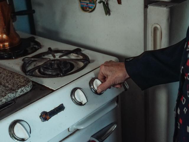 Hand turning a burner knob on a gas stove