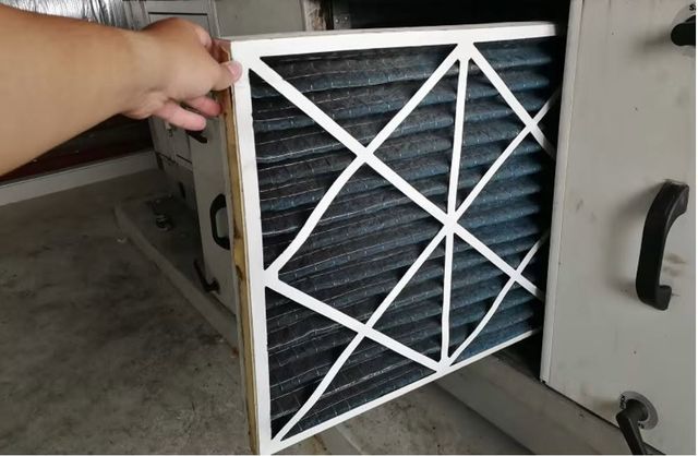 Dust caked pleated air filter being pulled out of an air handler