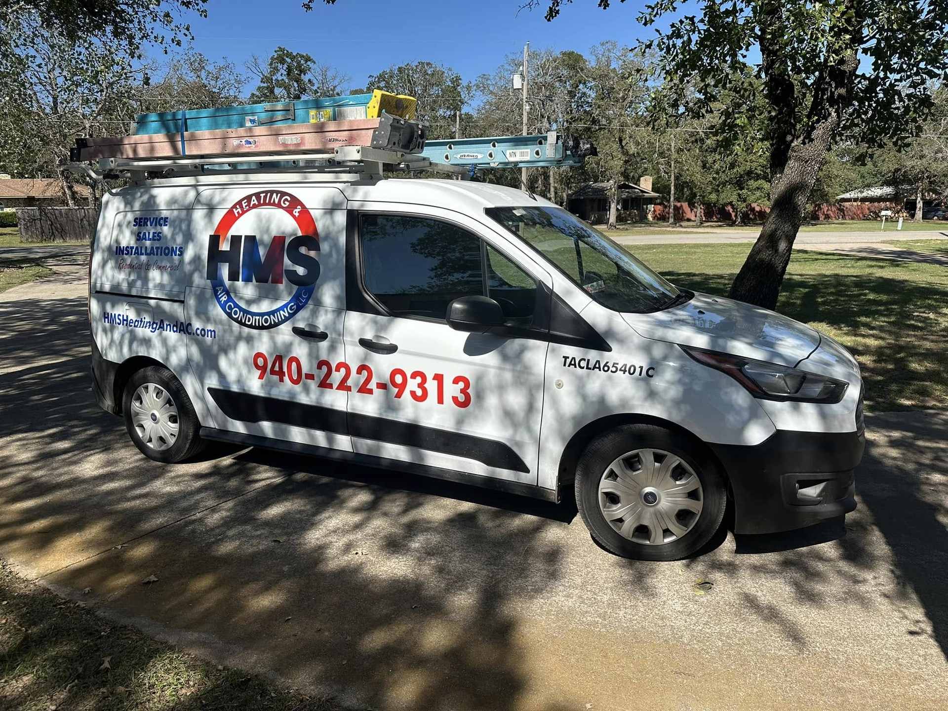 HMS Heating & Air Conditioning service van parked in the shade of trees