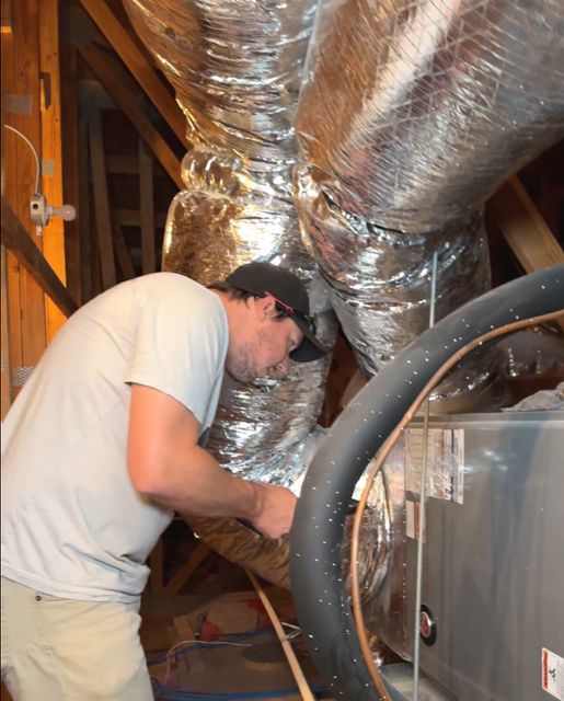 HMS technician connecting flex duct to an air handler in an attic