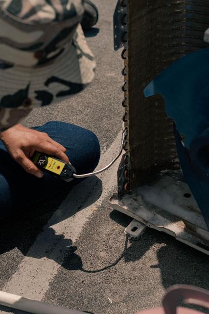 Technician kneeling beside an outdoor condenser during a service call