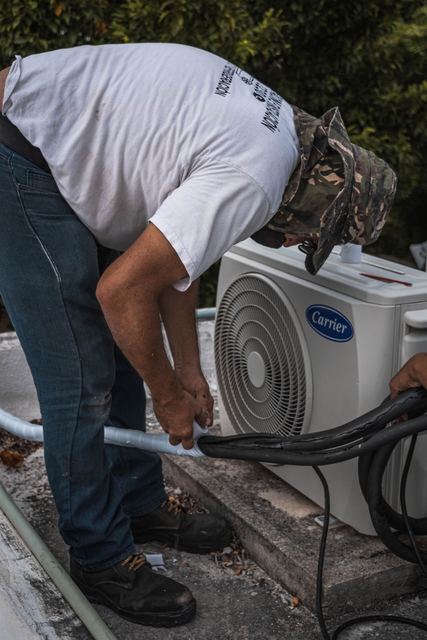 Technician connecting refrigerant lines at an outdoor unit