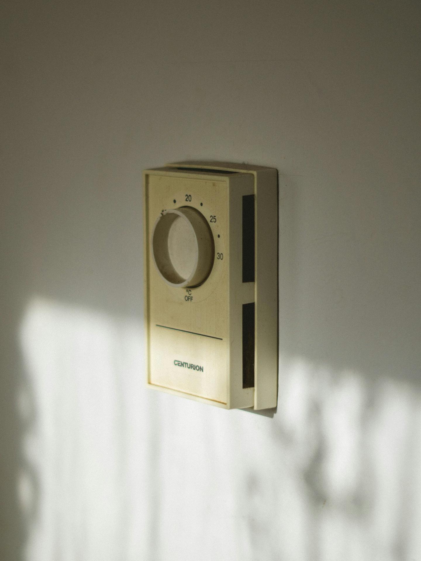Old beige dial thermostat mounted on a wall