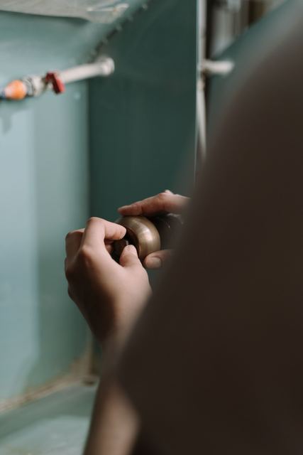 Hand checking pipework beneath a sink