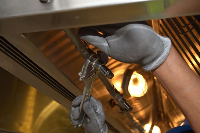 Technician working with a wrench beneath a water tank