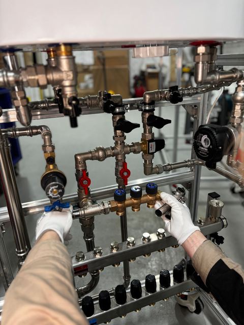 Gloved hands opening ball valves on a pipe manifold