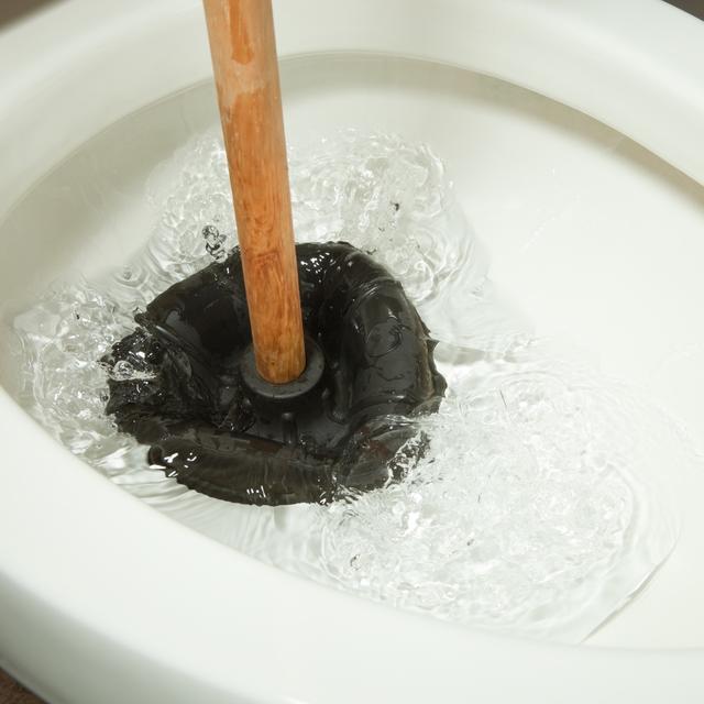 Plunger working in a toilet bowl to clear a clog