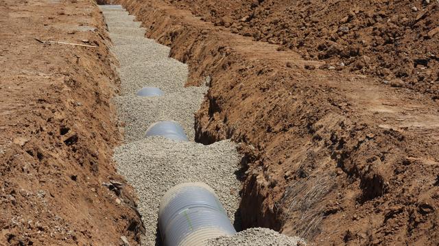 Drain pipe laid in gravel along the bottom of a trench