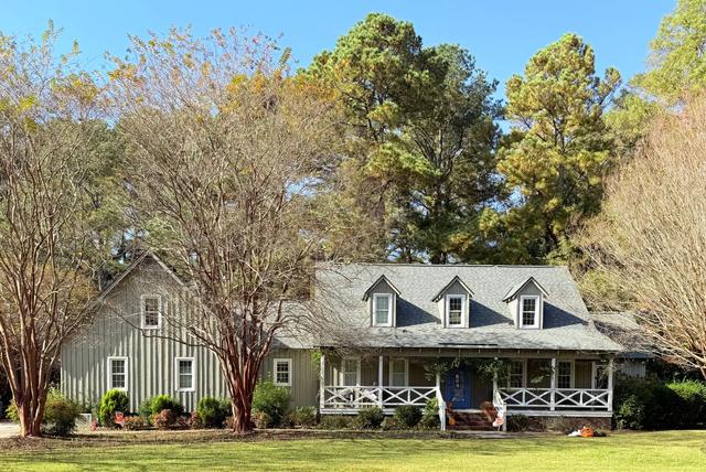 Home with a wide front porch under tall shade trees