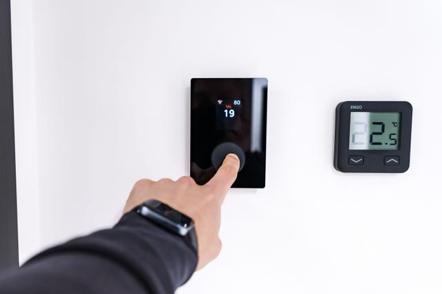 Hand adjusting the temperature on a smart wall thermostat