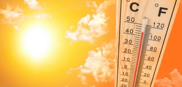 Outdoor thermometer reading close to 100 degrees Fahrenheit against a bright orange summer sky