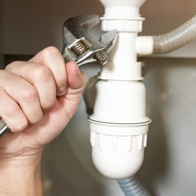 Hand tightening a white sink P-trap connection with an adjustable wrench